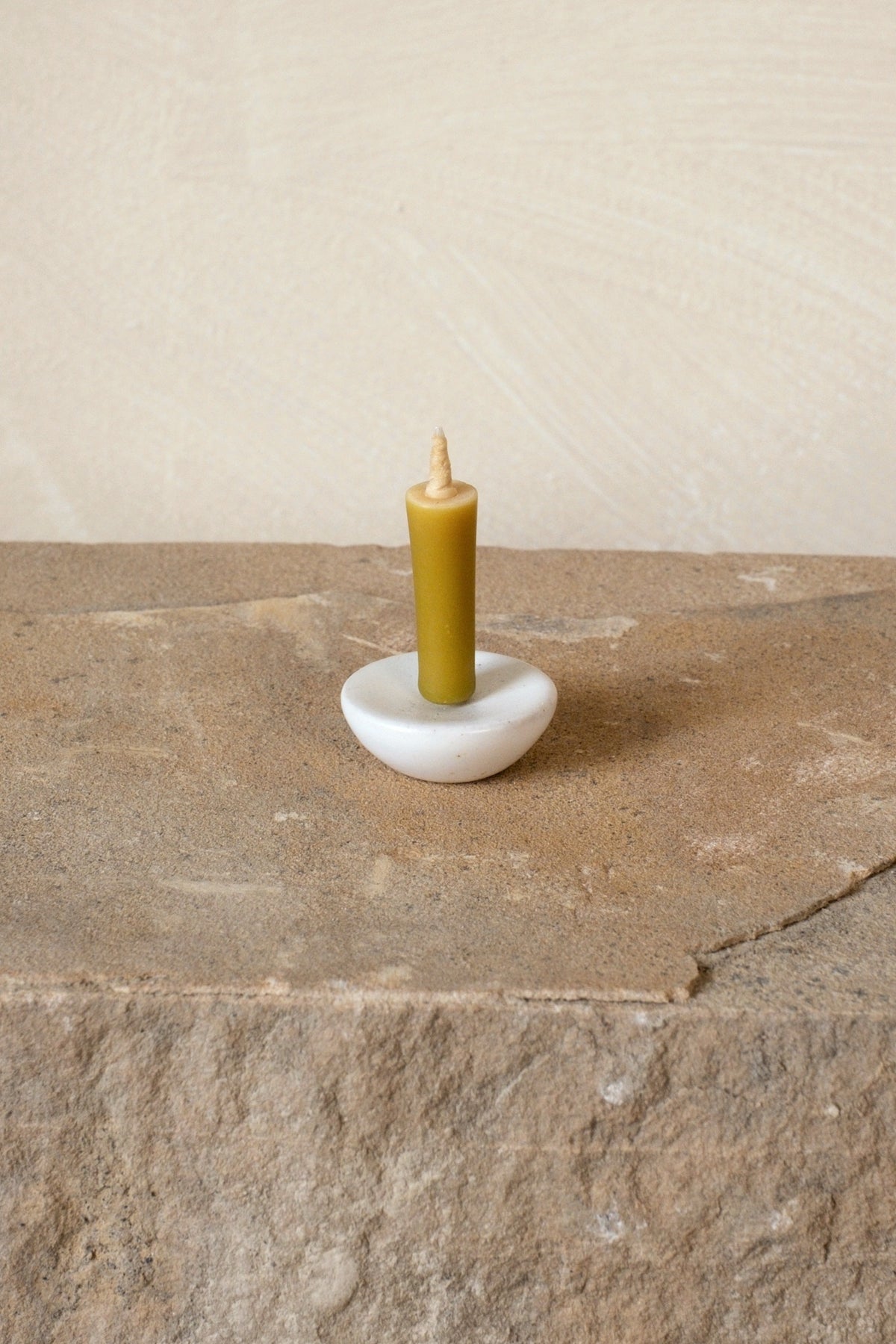 Daiyo rice wax candle in a white circle stand on stone