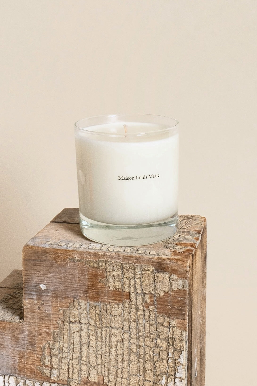 Maison Louis Marie candle in glass on a weathered wood pedestal